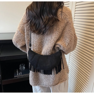 Detailed view of black suede crescent bag featuring long fringe tassels and knotted shoulder strap