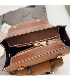 Dettaglio dell'interno della borsa in pelle marrone con tasca a zip e fibbia magnetica dorata