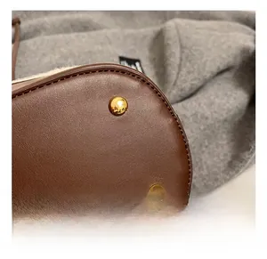 Detailed close-up of the dark brown leather bag base with protective gold metal feet