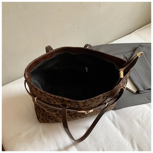 Macro detail of large leopard print tote bag with brown leather handles and gold hardware