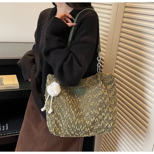 Detail view of green tweed tote bag featuring a leather strap and plush doll pendant