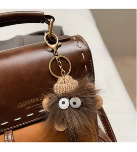 Dettaglio di un portachiavi a forma di bambola di peluche marrone su una borsa in pelle