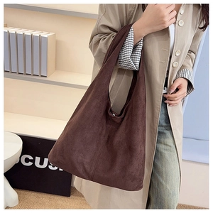 Side view of a large brown suede tote bag worn with a stylish long khaki coat