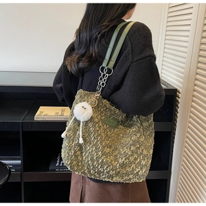 Detail of green fleece tote bag with leather strap and plush charm on a model