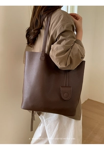 Close-up of deep brown lychee textured leather bucket bag with a side round pouch detail