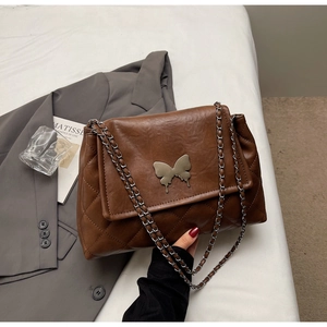 Détail du sac en cuir matelassé marron avec fermoir papillon et bandoulière chaîne