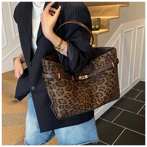 Chic leopard print tote bag with brown leather handles worn by a model in a stylish setting