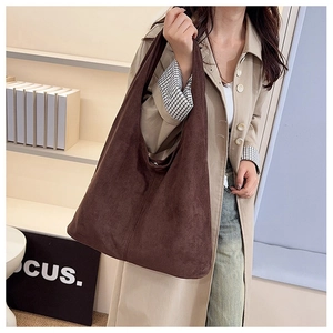 Detail view of a large brown suede-like tote bag worn over the shoulder for daily commuting