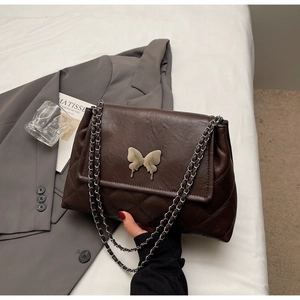Détail du sac en cuir matelassé marron foncé avec fermoir papillon argenté et chaîne