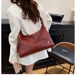 Gros plan du sac hobo en cuir bordeaux avec pendentif argenté et perles en bois rétro