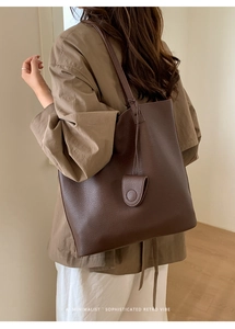 Detail of retro coffee brown tote bag showing textured leather and matching charm