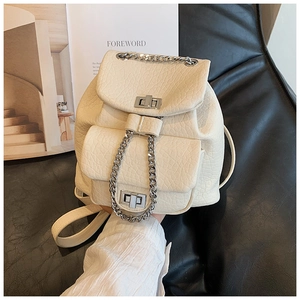 Detail of off-white faux leather backpack with silver chain and twist lock on dark background