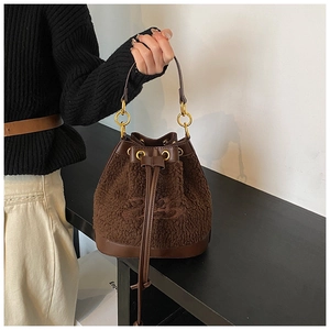 Close-up of brown faux shearling bucket bag with leather drawstring and gold hardware