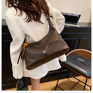 Détail du sac cabas en cuir marron foncé avec zip trèfle et accessoire de perles colorées