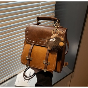 Dettaglio dello zaino vintage in pelle bicolore con cuciture a mano e ciondolo peluche