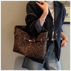 Detailed close-up of leopard print tote bag featuring brown leather trim and golden lock