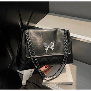Gros plan d'un sac cabas matelassé noir avec fermoir papillon argenté et bandoulière chaîne