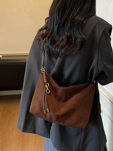 Vintage dark brown suede shoulder bag with tassel detail shown on a female model