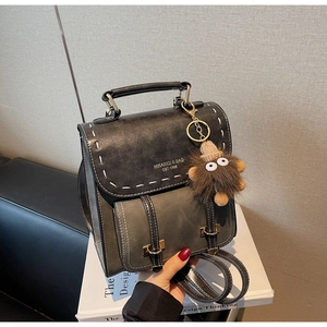 Dettaglio dello zaino vintage antracite con cuciture bianche e ciondolo di peluche