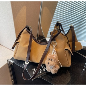 Dettaglio della borsa retrò in pelle scamosciata con finiture in pelle marrone e charm