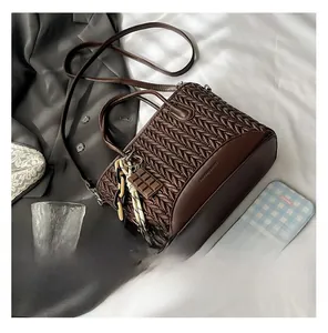 Detailed close-up of dark brown woven handbag featuring elegant V-pattern embroidery