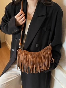 Brown suede crescent bag with tassels shown on a model for a vintage bohemian look