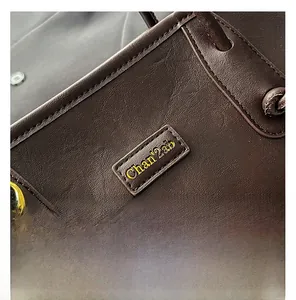 Detail of dark brown leather tote bag showing fine stitching and branded logo patch