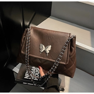 Vue détaillée du sac matelassé marron foncé avec boucle papillon en métal argenté