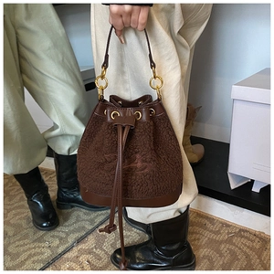 Detail shot of plush brown teddy bucket bag with leather drawstring and gold rings