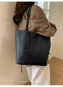 Detail of minimalist black pebbled leather tote bag with long double shoulder straps