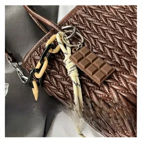 Detail view of deep brown woven leather bag with unique silicone pendant and chain