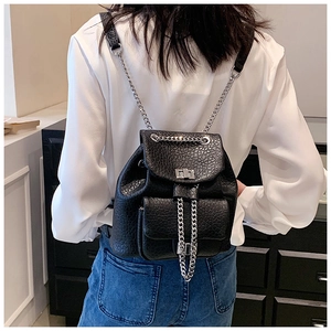 Detail of black pebbled leather mini backpack featuring silver chain straps and turn-lock