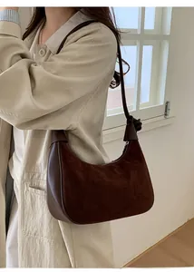 Detail of dark brown retro crescent bag made of suede and smooth leather on shoulder