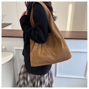 Side view of large brown suede hobo tote bag on model showing soft texture and capacity