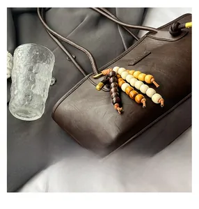 Detail of dark brown tote bag with lychee texture and colorful wood bead tassel charm