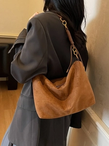 Chic brown suede hobo bag with a gold chain woven leather strap on a model shoulder