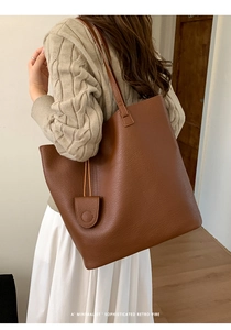 Detail of dark brown pebble leather tote bag with retro minimalist vibe and sleek texture