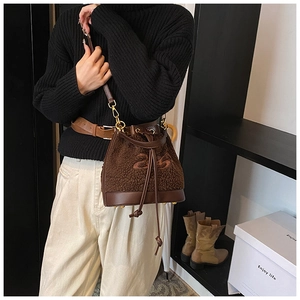 Detail of plush bucket bag featuring brown faux shearling texture and number embroidery