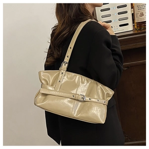 Detail of glossy apricot underarm bag with decorative metal eyelet buckles and strap