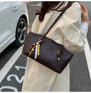 Detailed view of coffee brown faux leather tote with vintage wooden bead tassel accessory