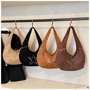 Detail of four suede hobo bags with metallic rivet star patterns hanging on display