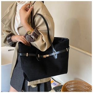 Detail of black suede tote bag with gold metal buckle and elegant belted strap design