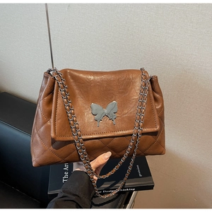 Détail du sac matelassé marron foncé avec boucle papillon argentée et bandoulière chaîne