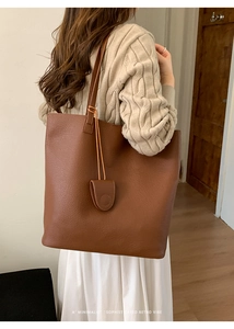 Deep brown leather tote bag with pebble texture and matching pendant charm detail