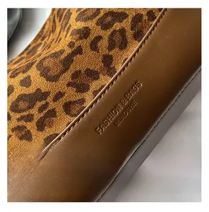 Detail view of leopard print fabric and brown leather with stamped branding on a trendy bag