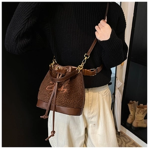 Detail of plush brown bucket bag with leather drawstring and abstract embroidery