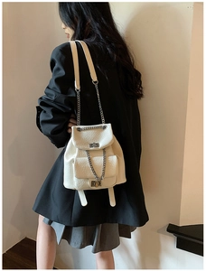 Detailed shot of white lychee leather backpack with chain straps and metal twist-lock pockets