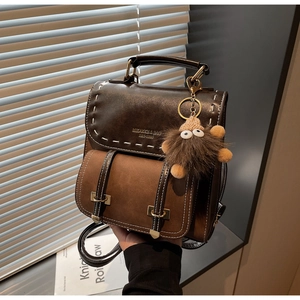 Dettaglio zaino vintage marrone con cuciture a contrasto e ciondolo di peluche