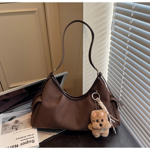 Dettaglio di una borsa a mezzaluna in camoscio marrone scuro con tasche e ciondolo cane