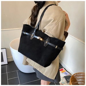 Detail view of large black suede tote bag with leather strap and golden metal buckle